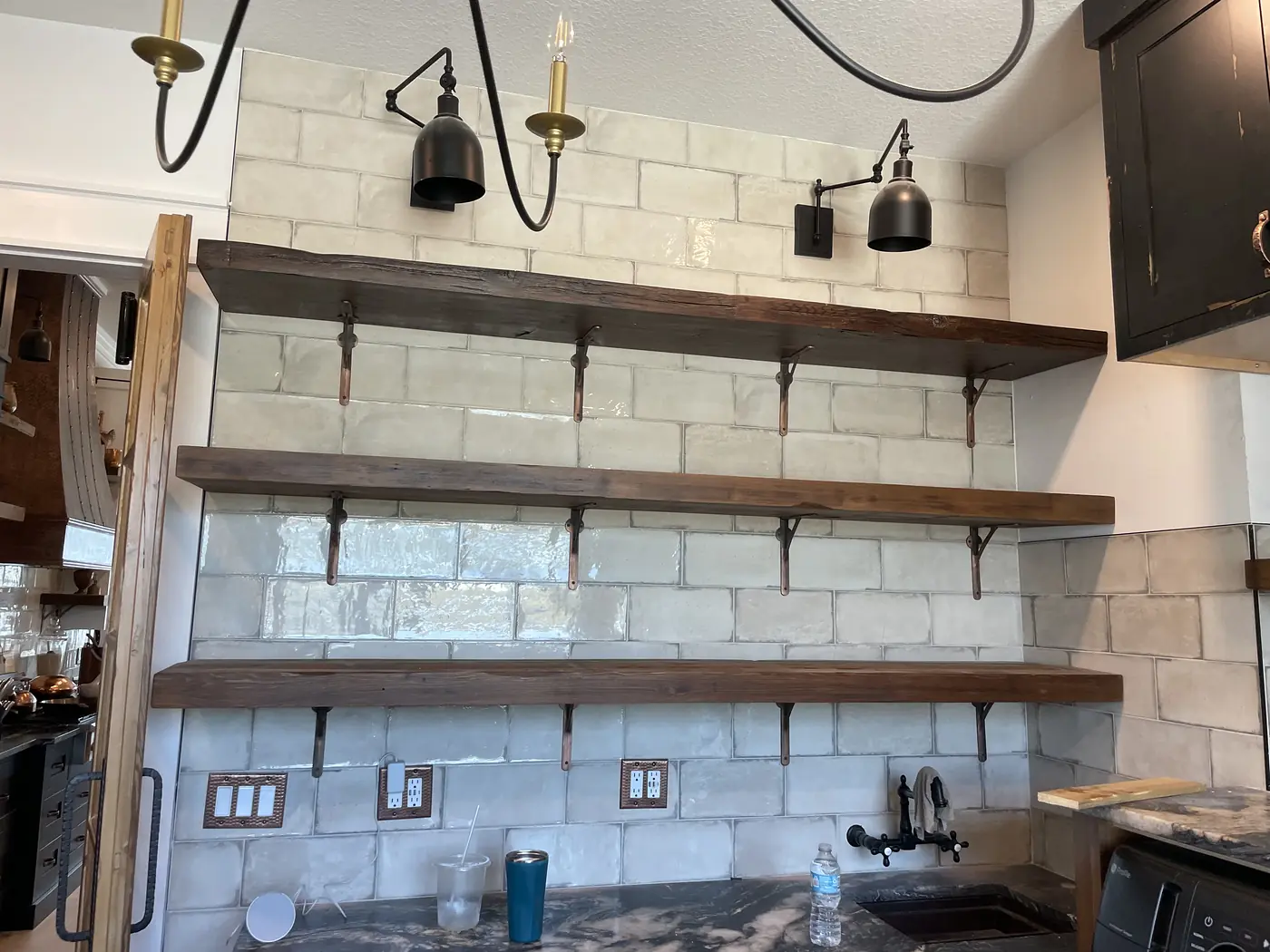 Thick timber shelves on iron brackets fixed to a whitewashed brick wall