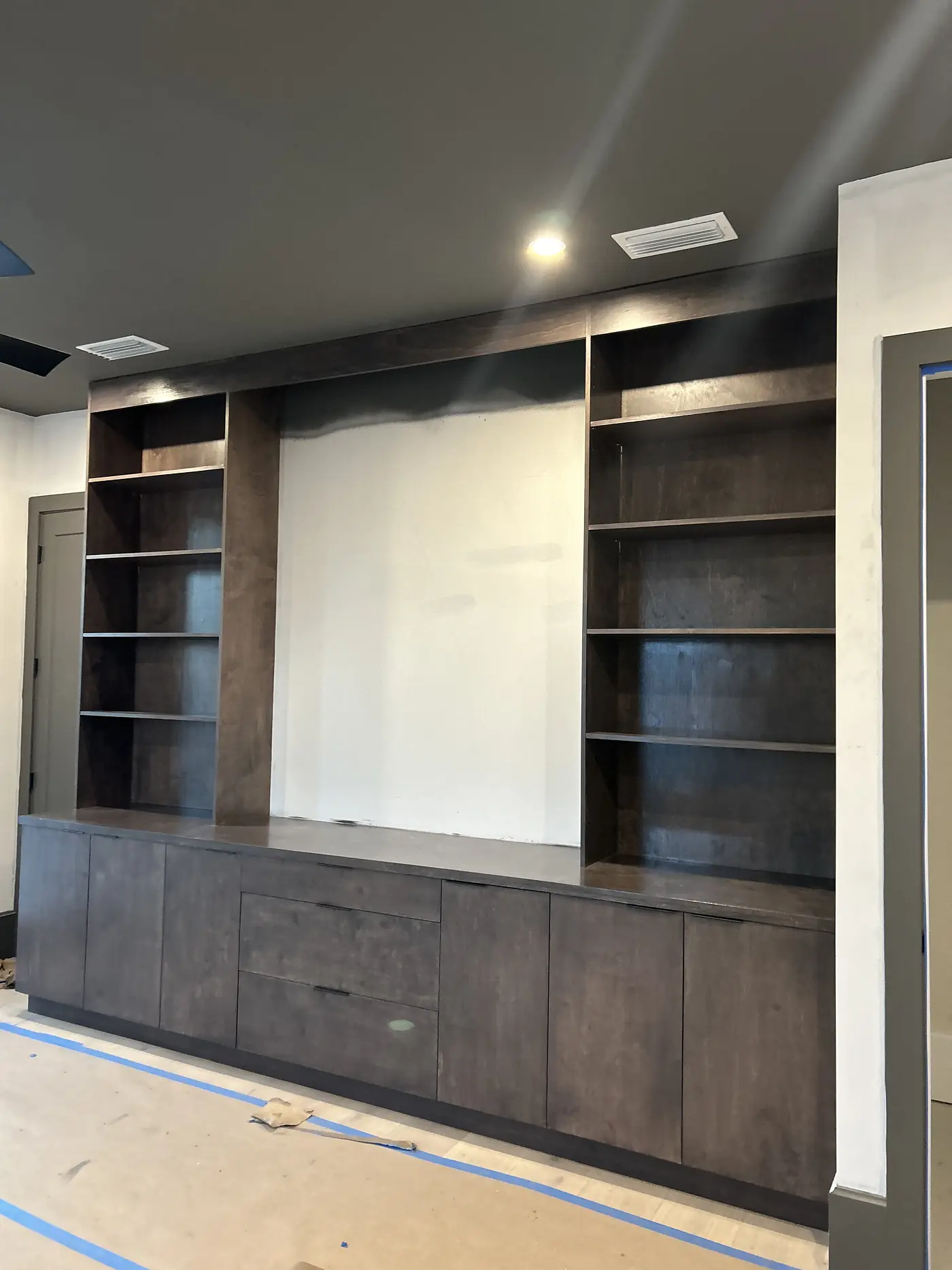 Dark stained media wall part way through installation with the shelves and base cabinets fitted