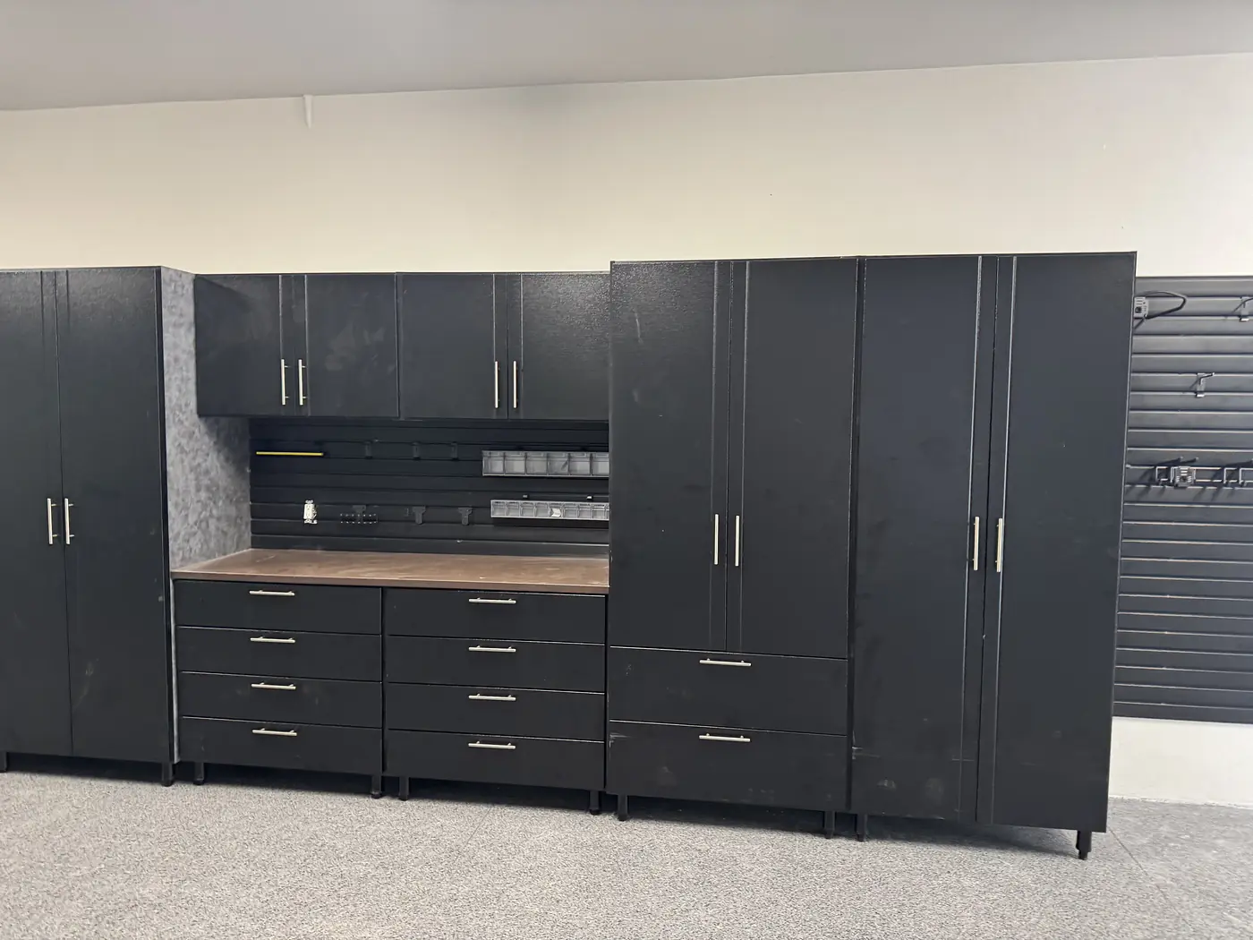 Run of black garage storage cabinets with a butcher block worktop and a bank of drawers