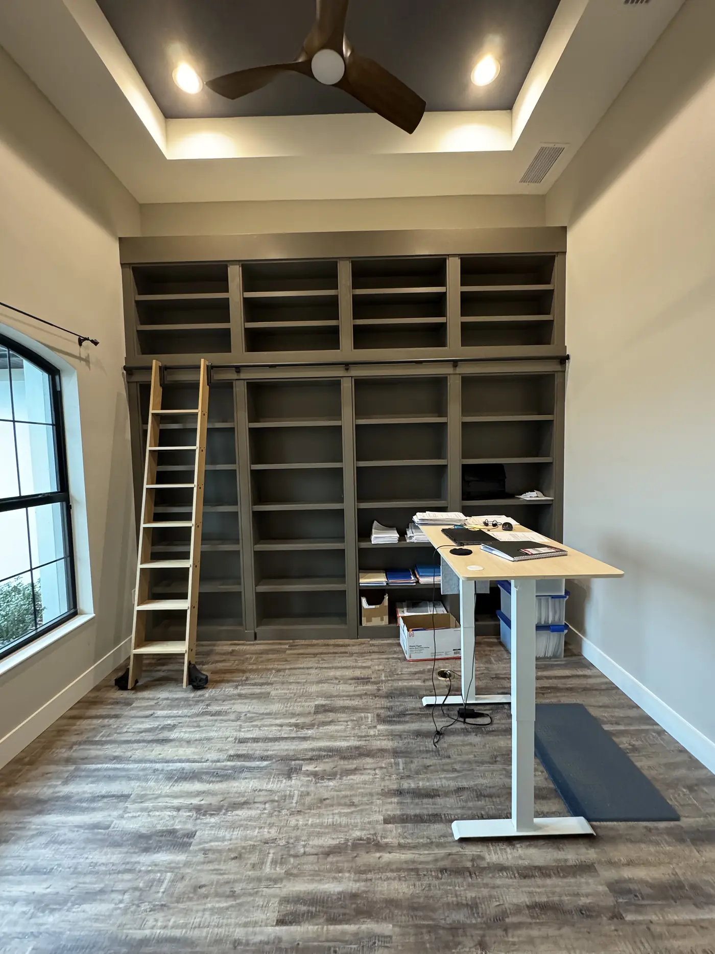 Floor to ceiling library shelving with a rolling ladder, photographed before finishing