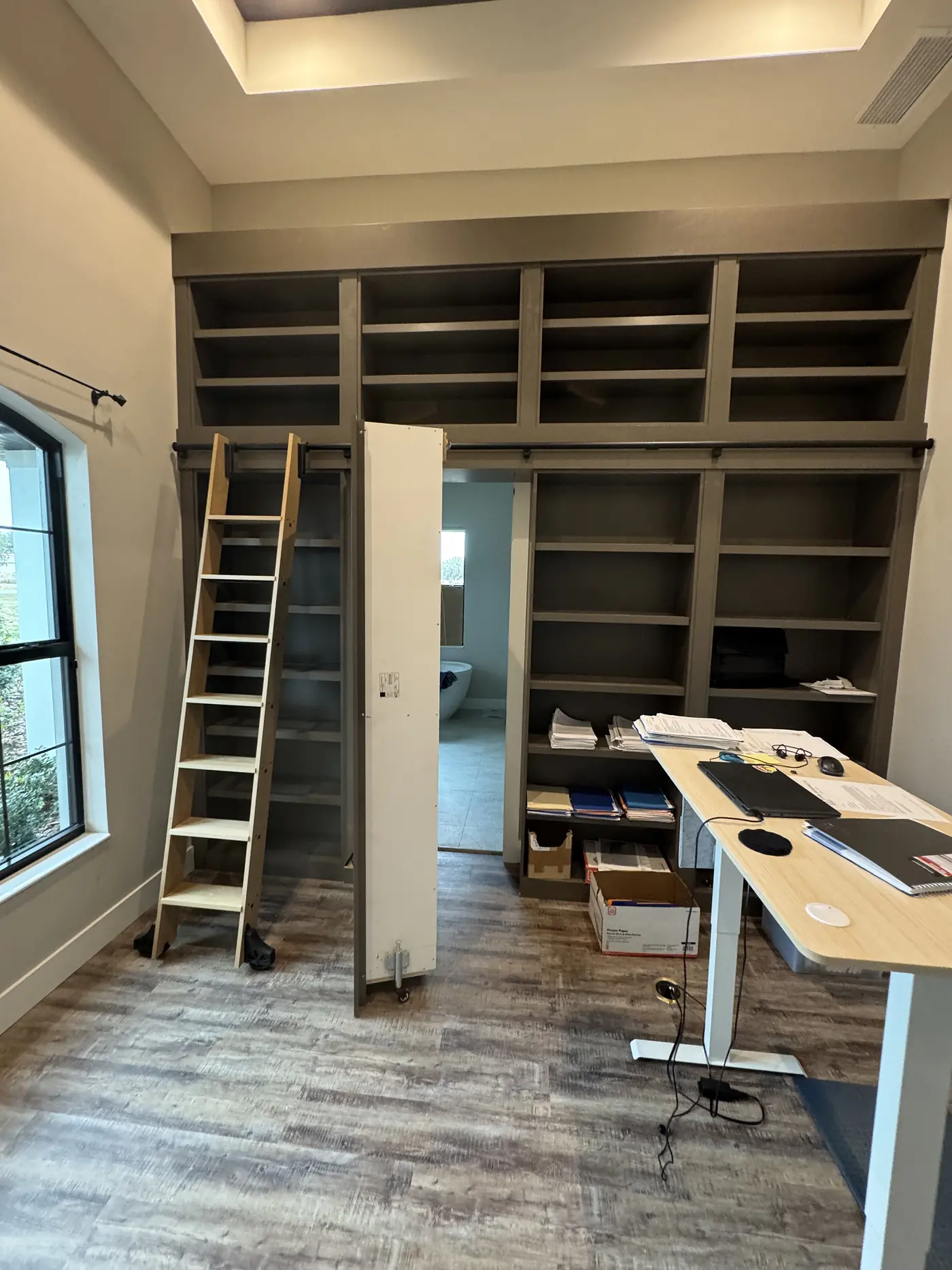 Library shelving carried wall to wall around a doorway with the ladder rail fitted