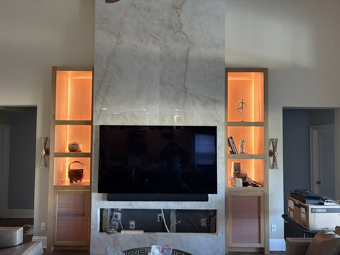 Marble fireplace surround with a wall mounted television and lit display niches either side