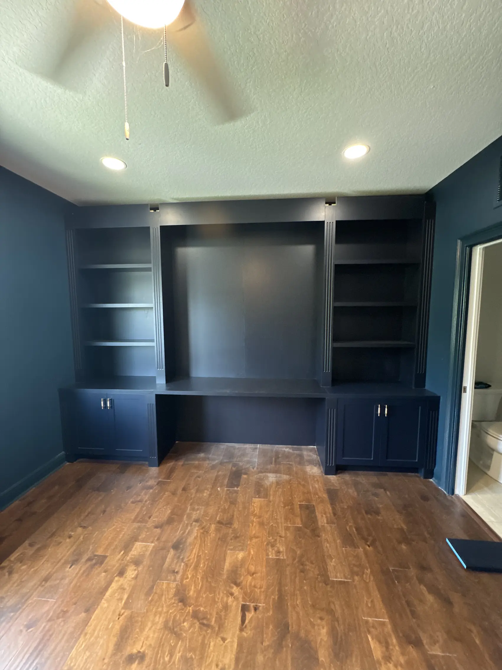 Navy built in desk with shelving above and cabinets below in a home office