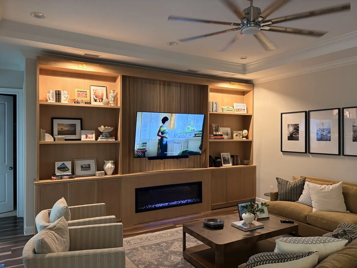 Built in oak media wall with open shelving, a linear fireplace and cabinets along the base
