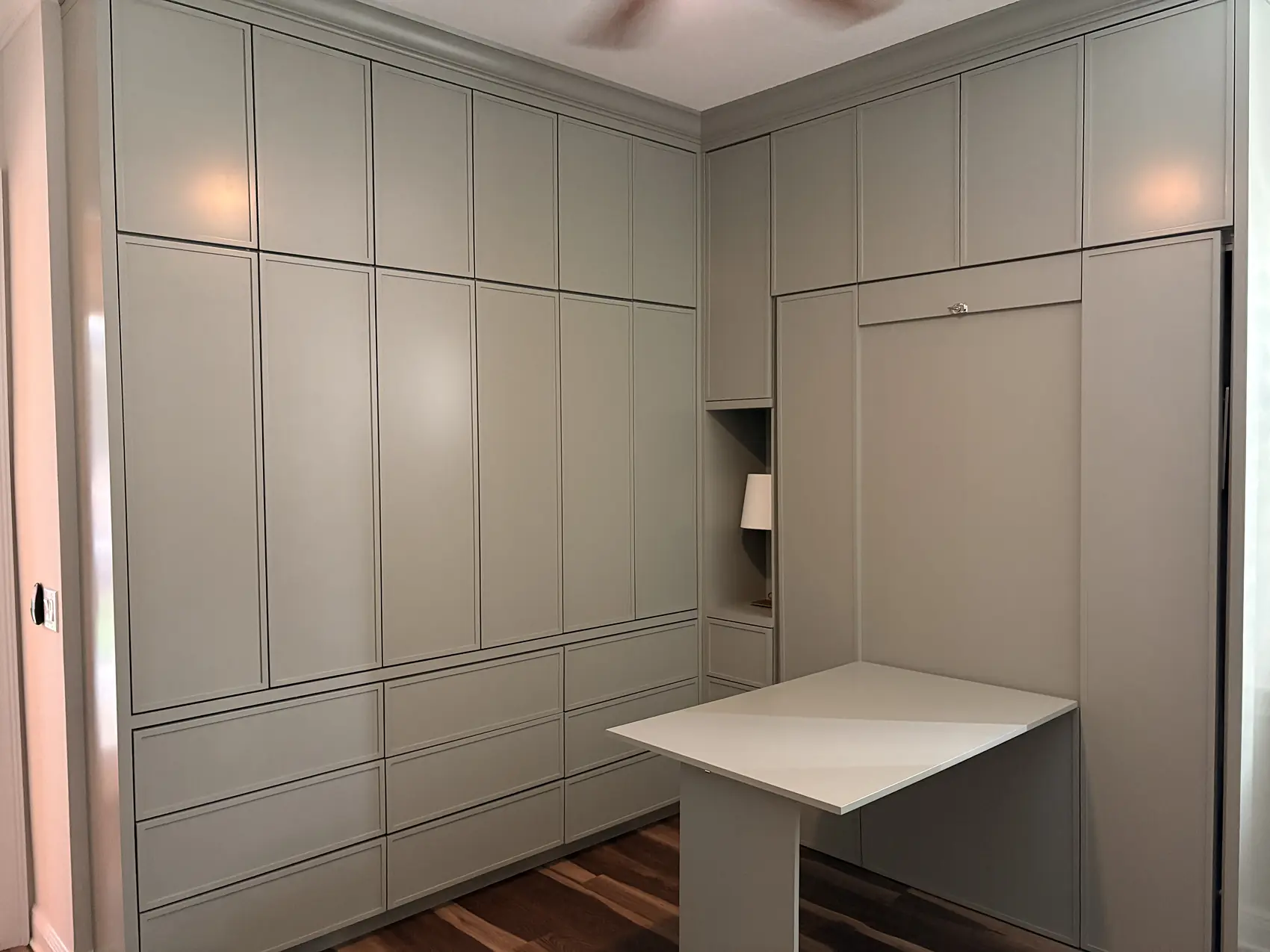 Floor to ceiling panelled wall with a wall bed and a fold down desk built into it