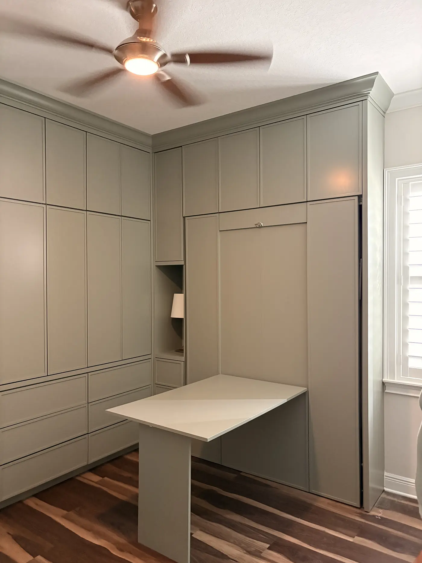 Panelled wall with a lit niche and the wall bed door closed flush into the panelling
