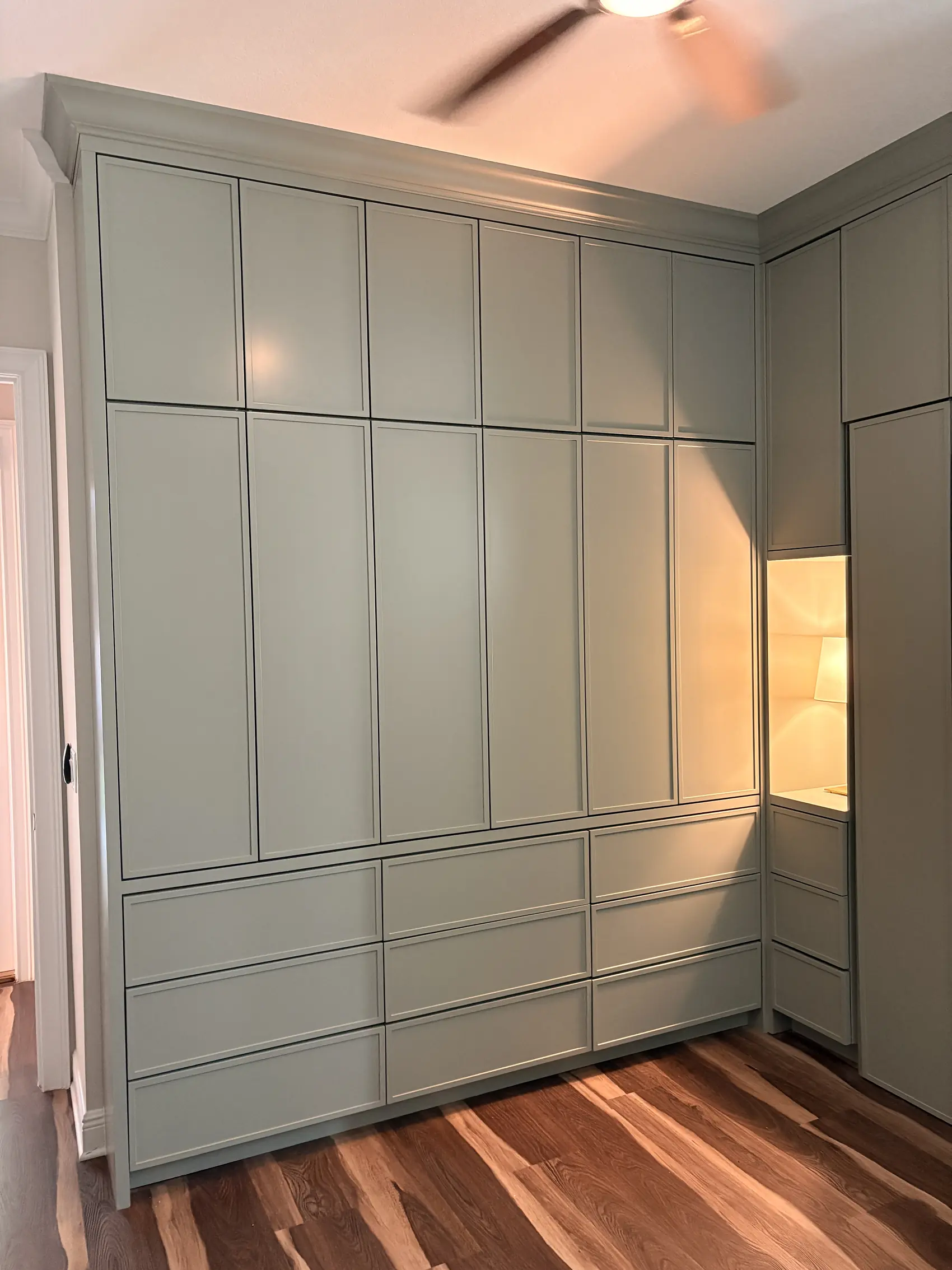 The full panelled wall with drawers along the base and a lit niche at one end