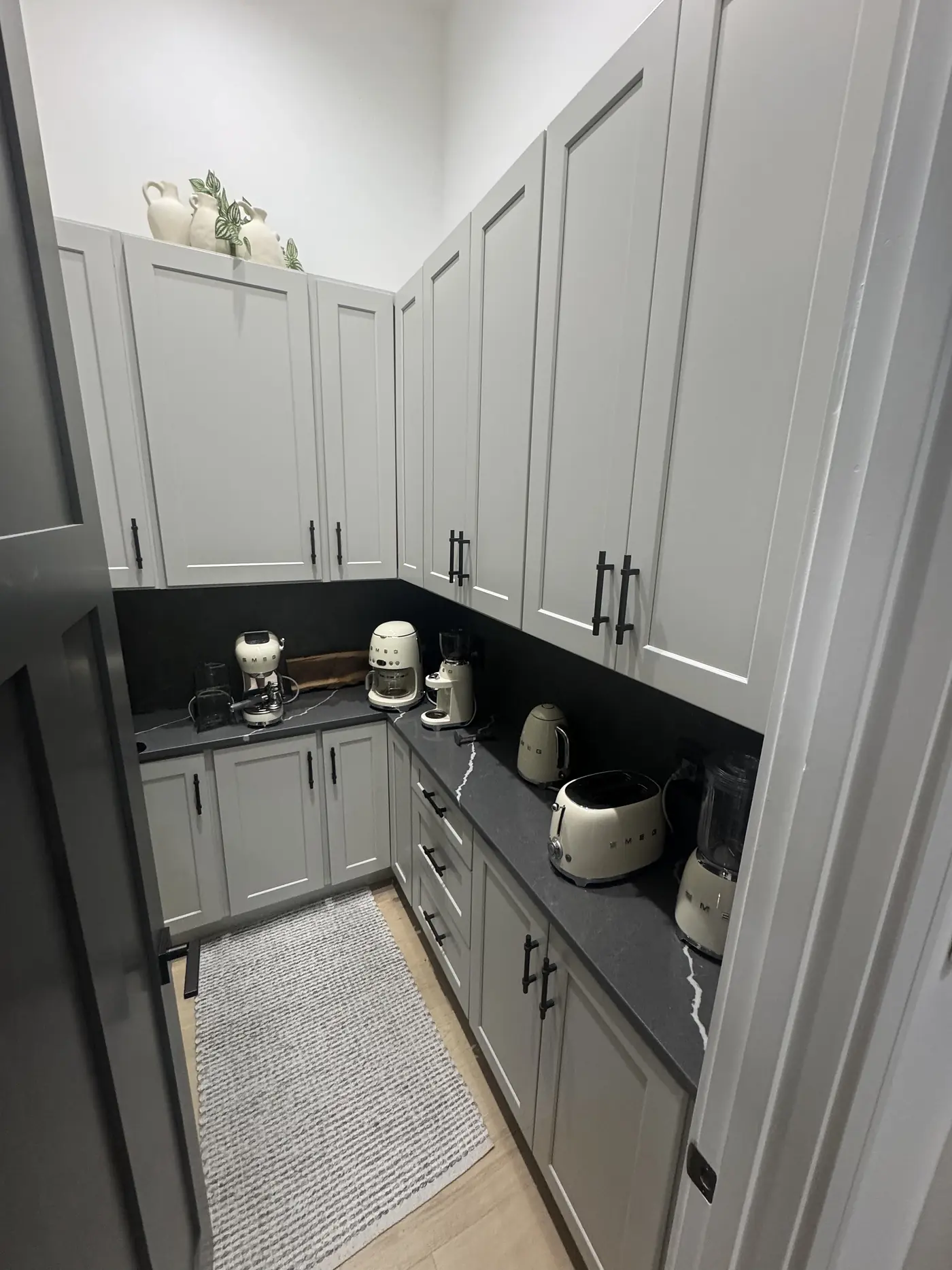 Corner of a grey pantry where two runs of cabinets meet