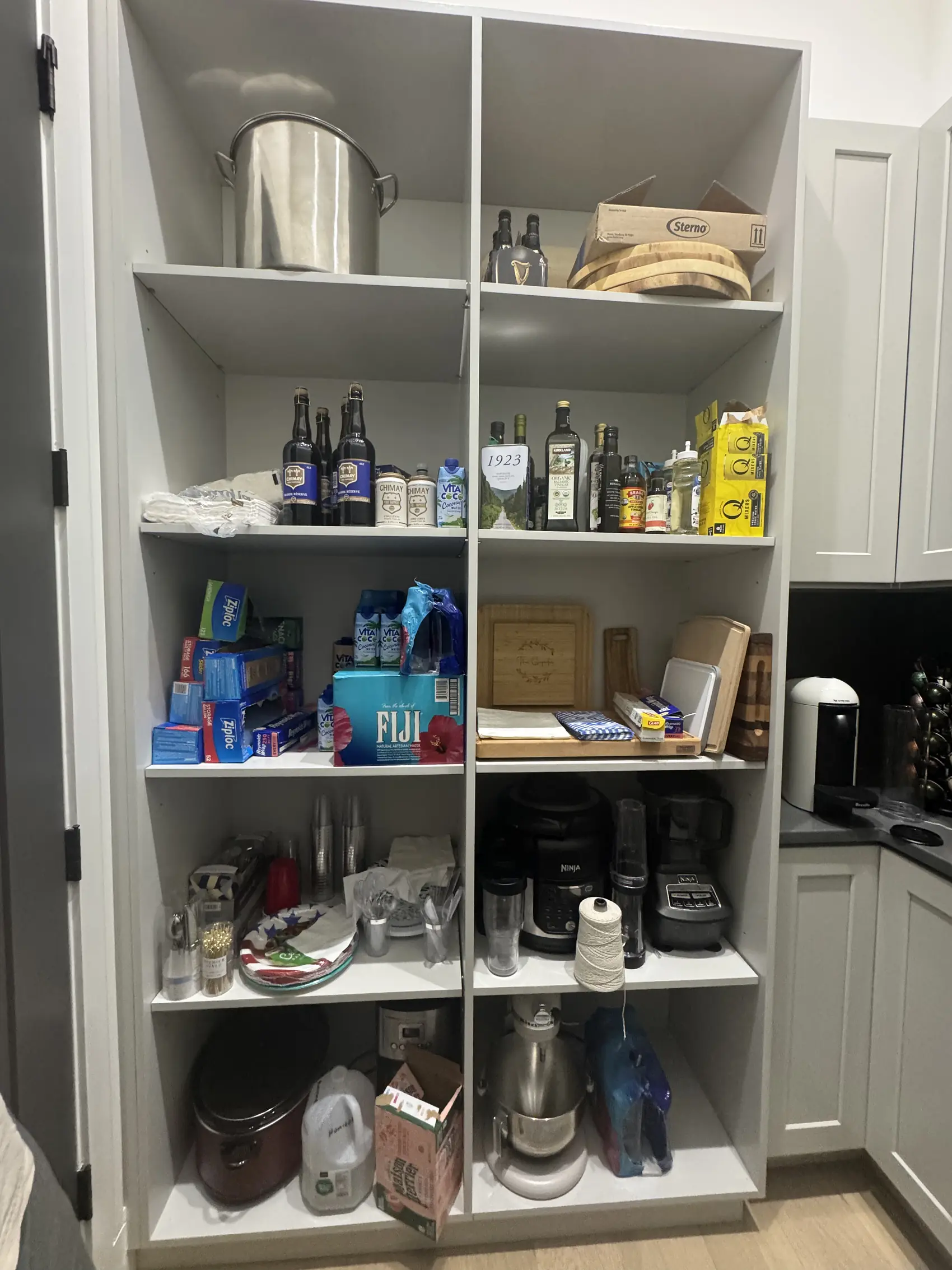 Tall pantry cabinet with its doors open showing the fixed shelving inside