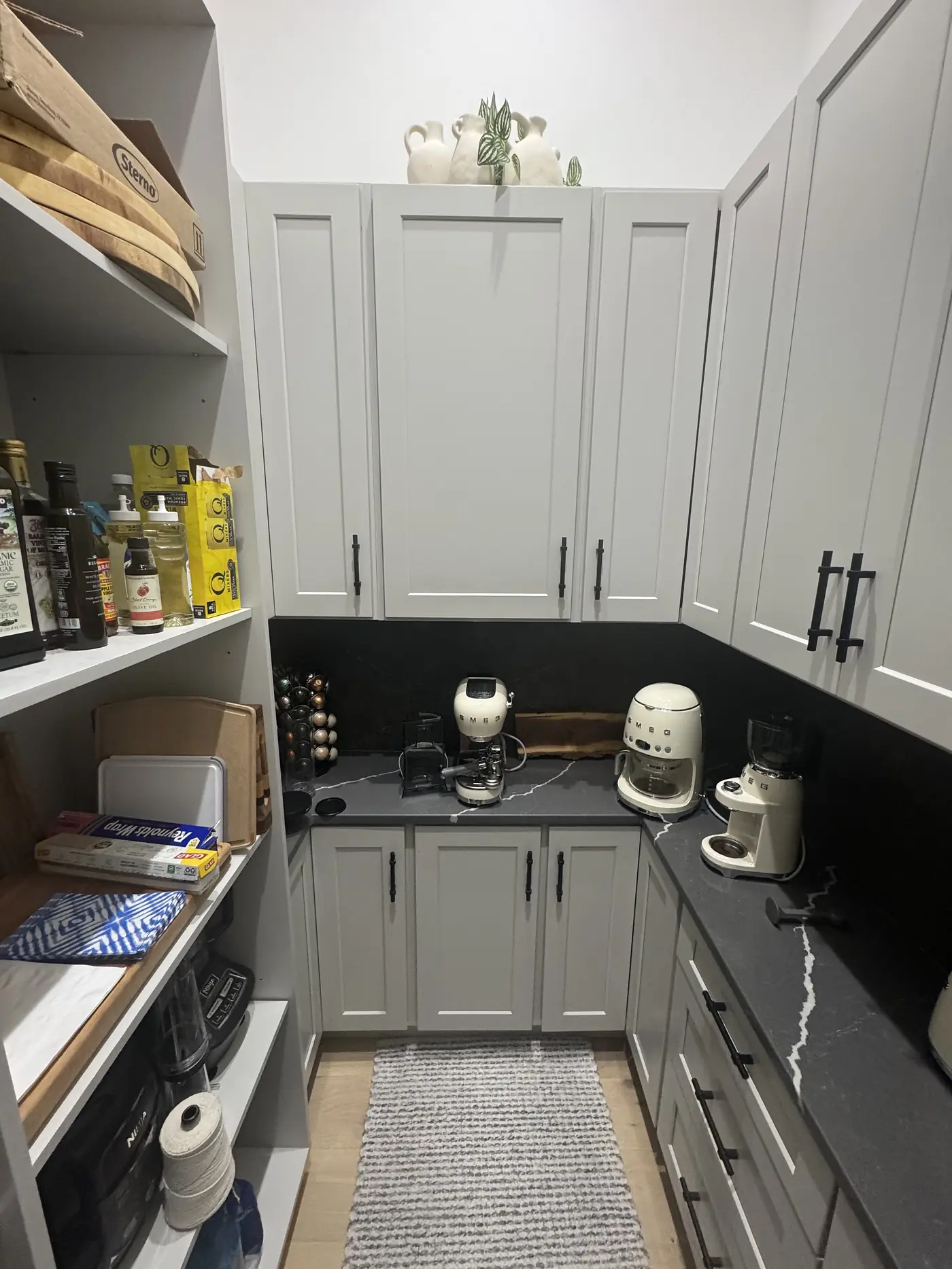 Full length of a grey butler pantry with cabinets on both sides