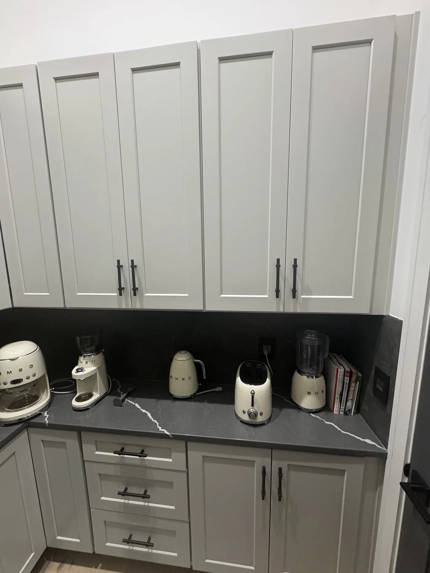 Upper cabinets carried to the ceiling above the counter run in a grey butler pantry