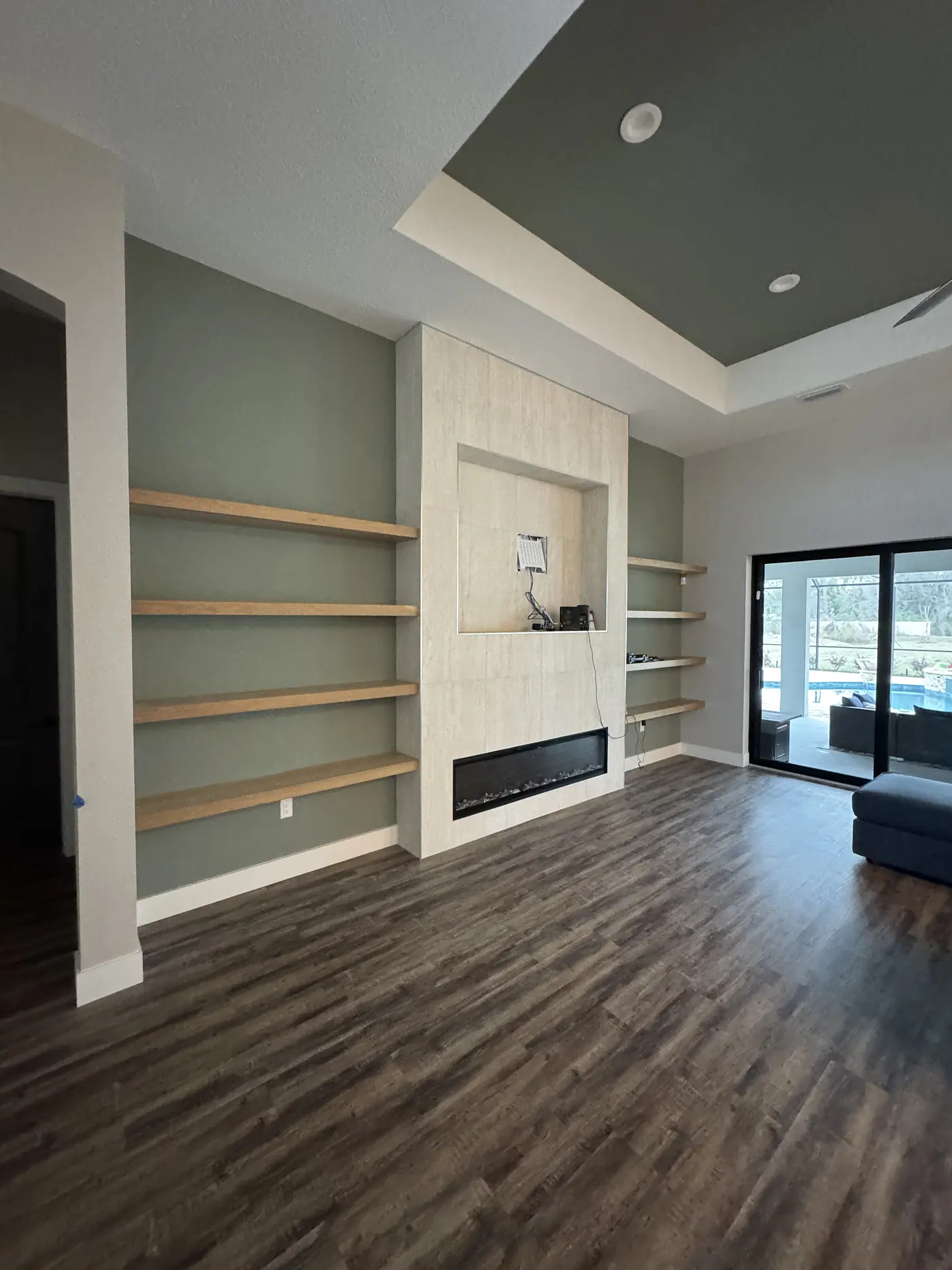 Floating shelves on a sage panelled wall above a linear fireplace