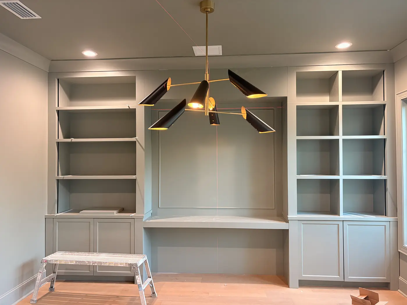 White built in desk with open shelving either side and cabinets below