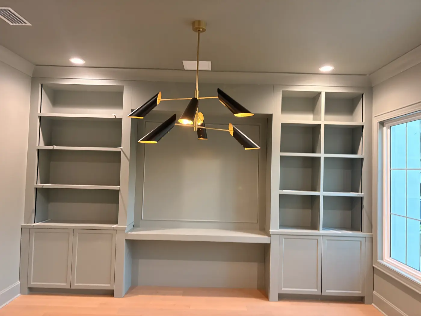 Built in desk and shelving painted white, seen from the side of the room