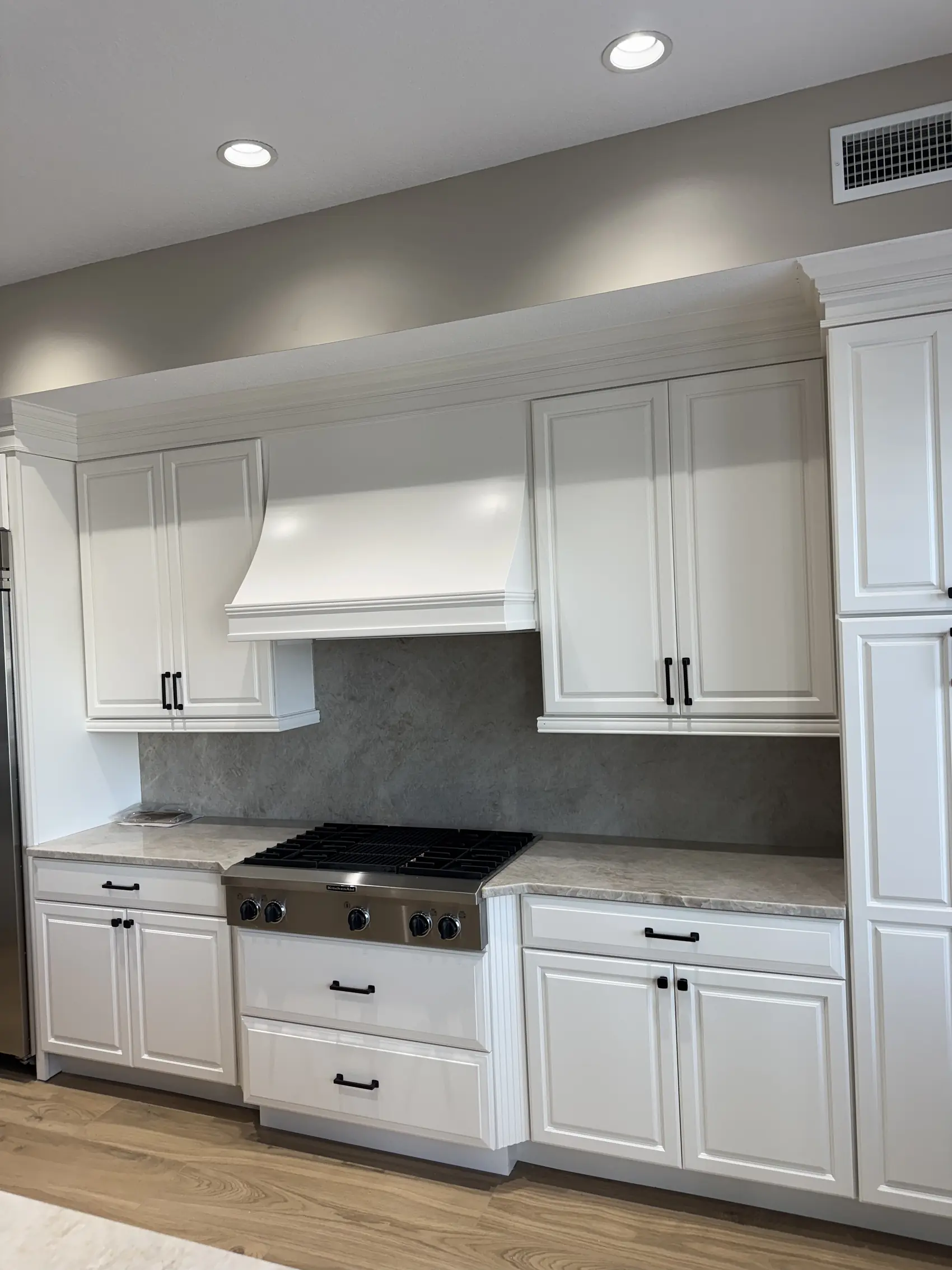 White shaker kitchen cabinets with a built up range hood and drawers under the cooktop