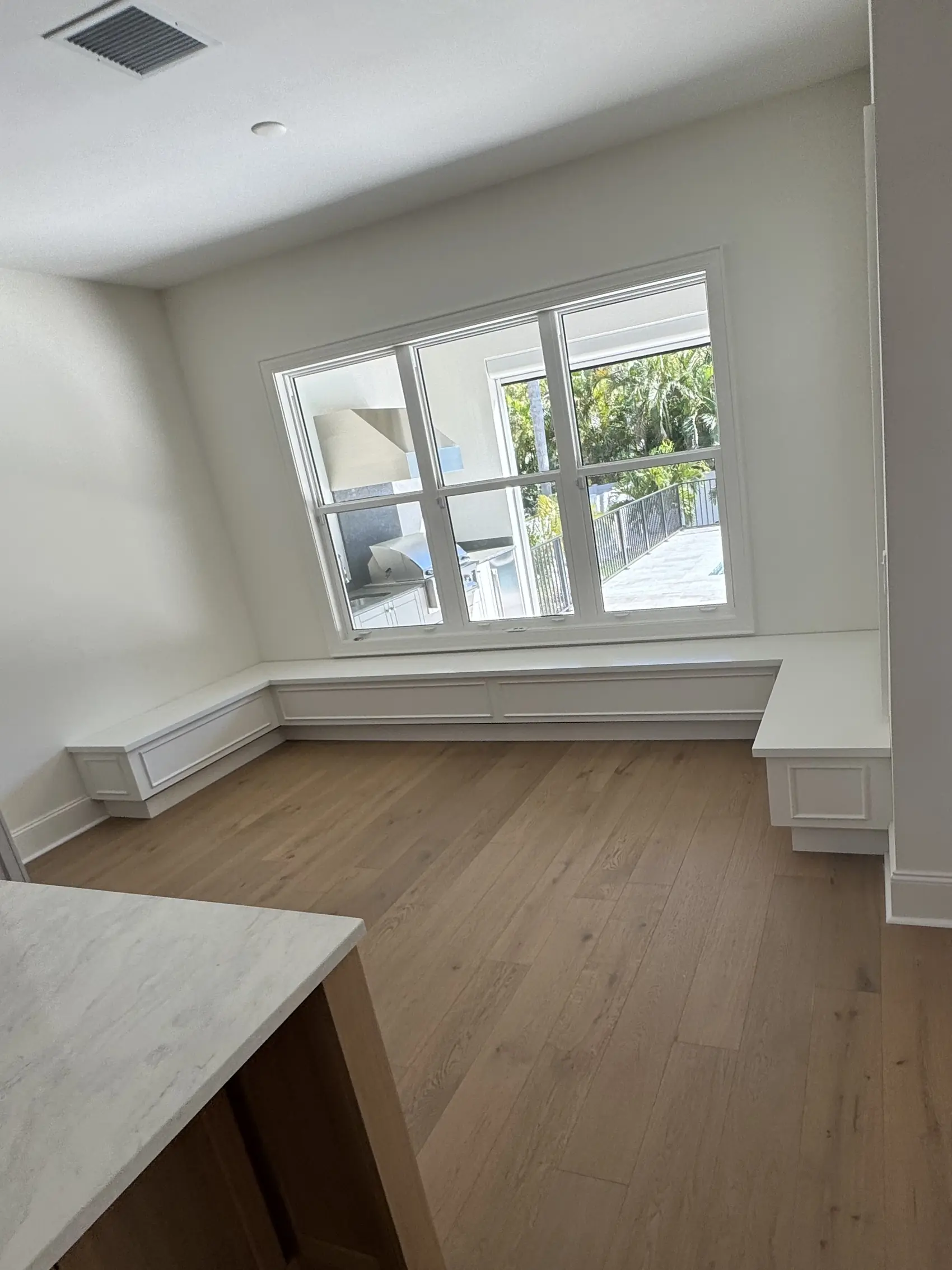 White window seat built along a bay of windows with panelled fronts