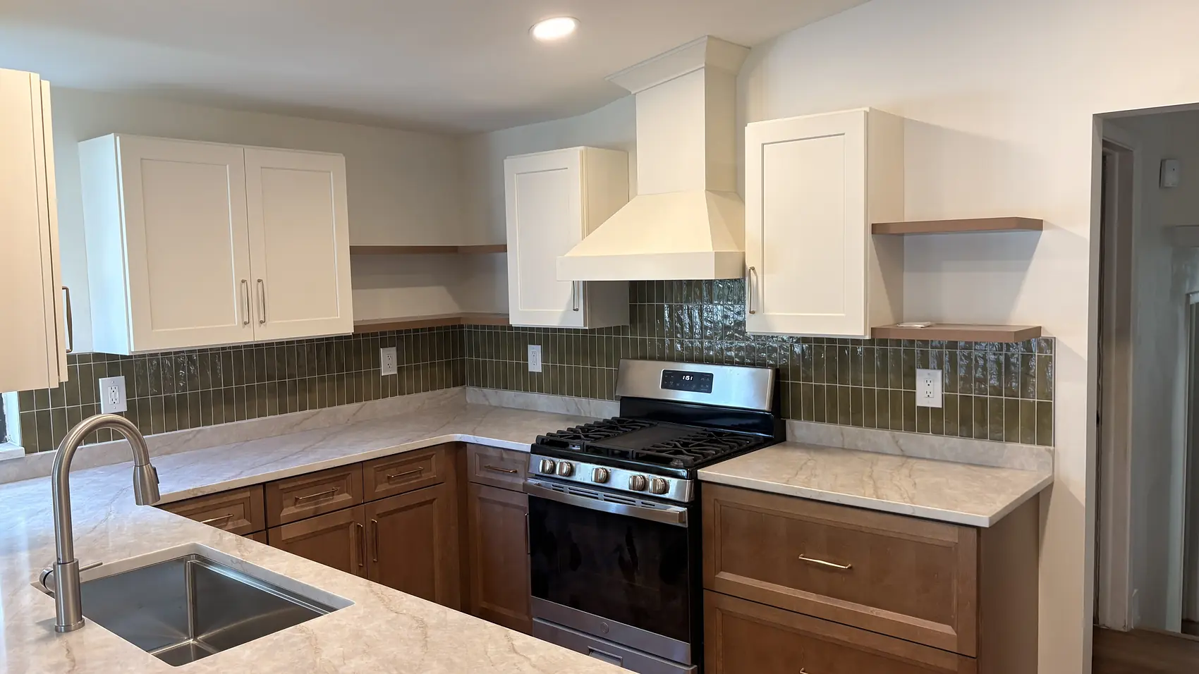 Wood kitchen cabinets with a green tile backsplash and stone counters